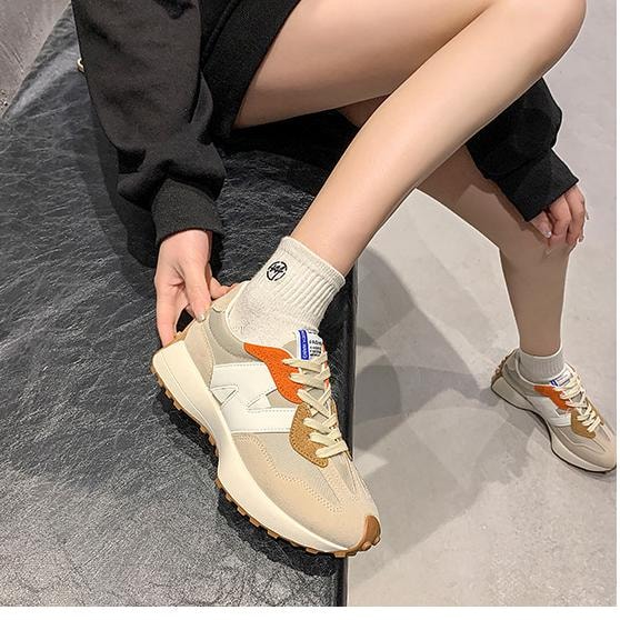 Sneakersy damskie beżowe z pomarańczowym detalem na nodze modelki